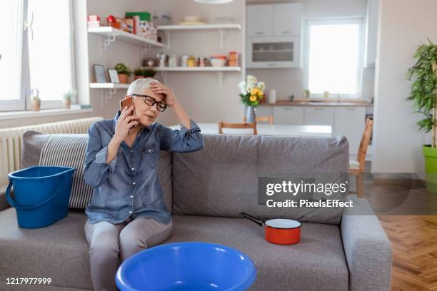 angry senior women talking on smartphone because of roof leaking - leaky roof stock pictures, royalty-free photos & images