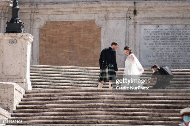 The bridegroom wears a kilt, the traditional Scottish dress, as a marrying couple takes photos on the Spanish Steps, aftger the authority ease...