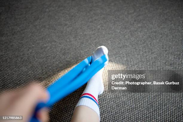 part of a runner woman stretching her leg and foot with a resistance band - calf human leg stock pictures, royalty-free photos & images