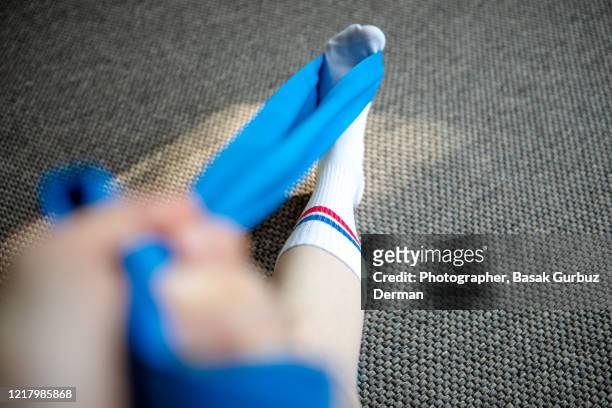 part of a runner woman stretching her leg and foot with a resistance band - adult gymnast feet stock-fotos und bilder