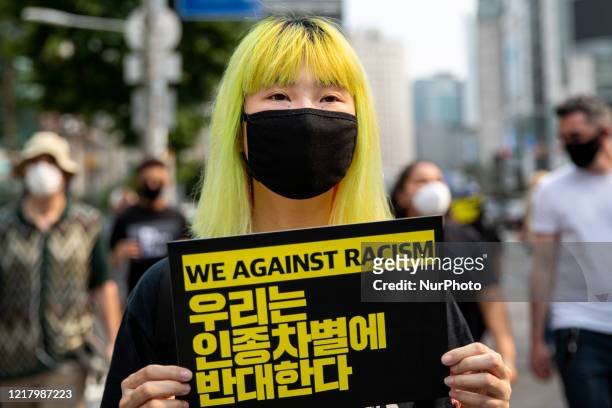 Woman holds a We Against Racism placard on June 06, 2020 in Seoul, South Korea. The Rally in solidarity with protests in the United States following...