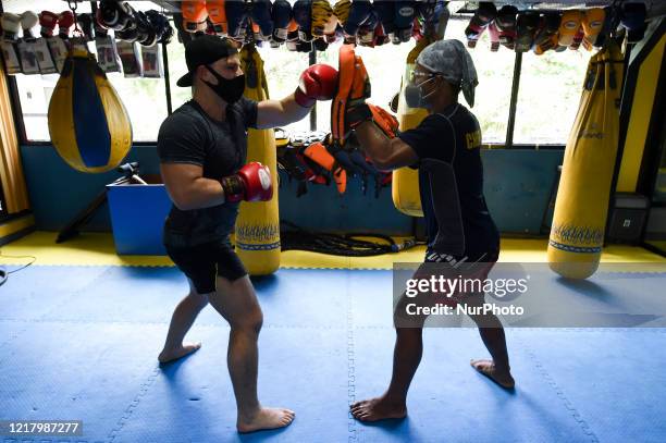 Muay Thai boxing enthusiast wear protective facemasks and a Thai instructor wear face masks to prevent COVID-19 coronavirus pandemic during a Muay...