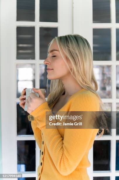 portrait of woman in yellow sweater holding mug - vapor da respiração imagens e fotografias de stock