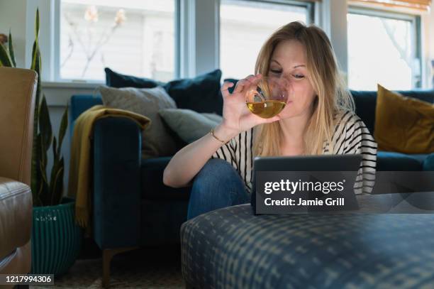 woman drinking wine and looking at tablet at home - epidemics stock pictures, royalty-free photos & images