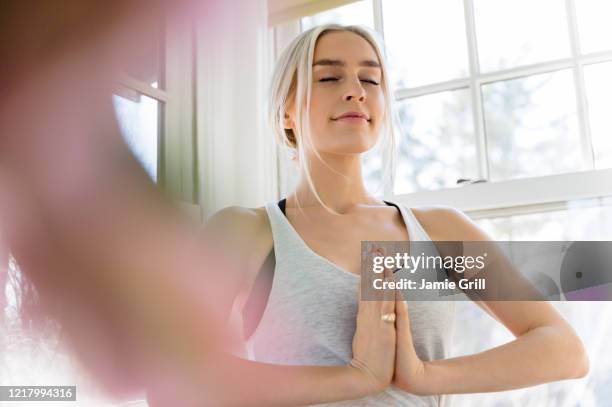 young woman in yoga pose - namaste stock-fotos und bilder