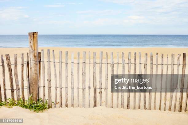 wooden fence at an empty beach against sea and sky - beach fence stock-fotos und bilder