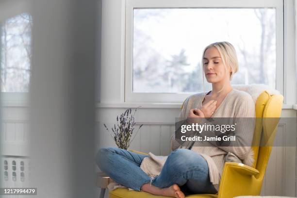 woman meditating at home - inhaling stockfoto's en -beelden