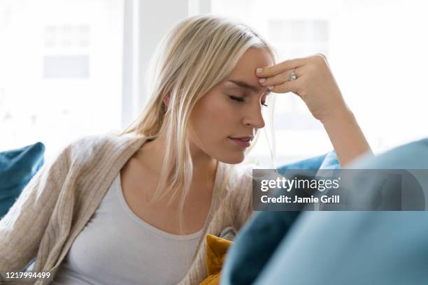 woman with headache siting on sofa - reizen stock-fotos und bilder