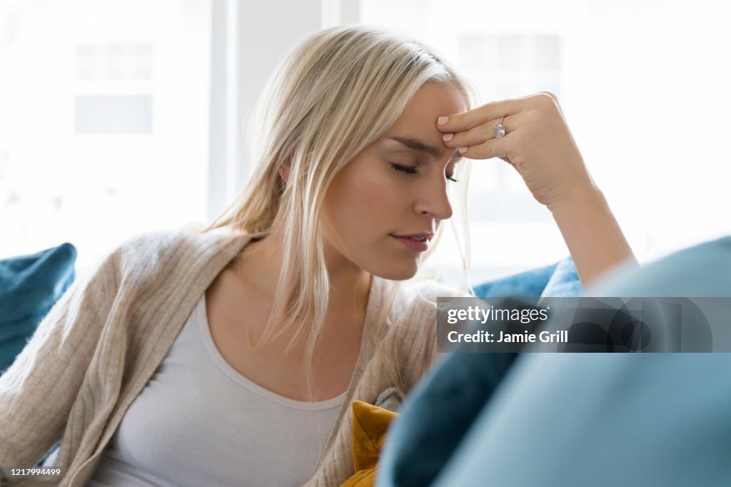 Woman with headache siting on sofa