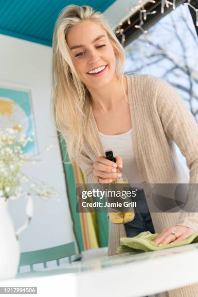 smiling woman cleaning tabletop with natural cleaning spray - lemon cleaning spray stock pictures, royalty-free photos & images