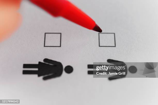 person marking with pen on male and female gender checklist - gender identity stockfoto's en -beelden