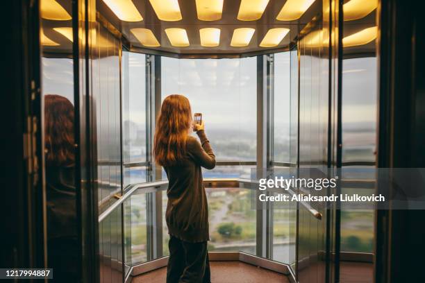 belarus, minsk, woman standing in transparent elevator - lift stock-fotos und bilder