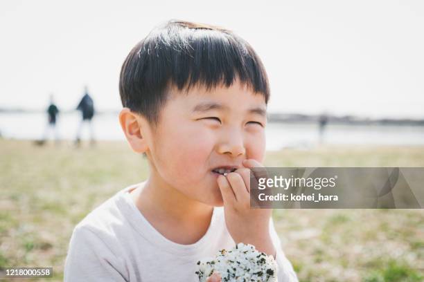 boy eating rice bowl in the park - rice ball stock pictures, royalty-free photos & images