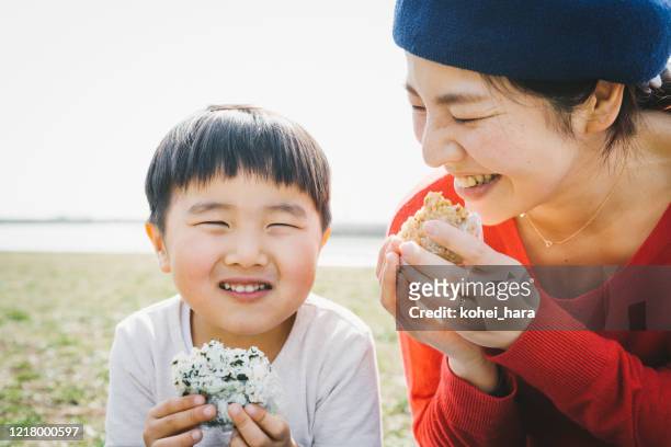 Mother and son eating rice bowl in the park