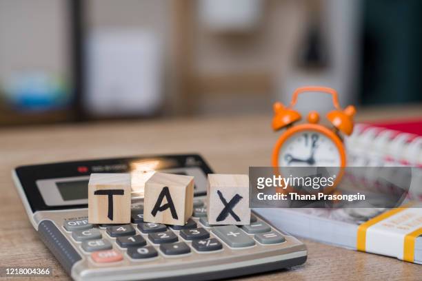 tax on wooden blocks on top of work desk space - filing documents stock pictures, royalty-free photos & images