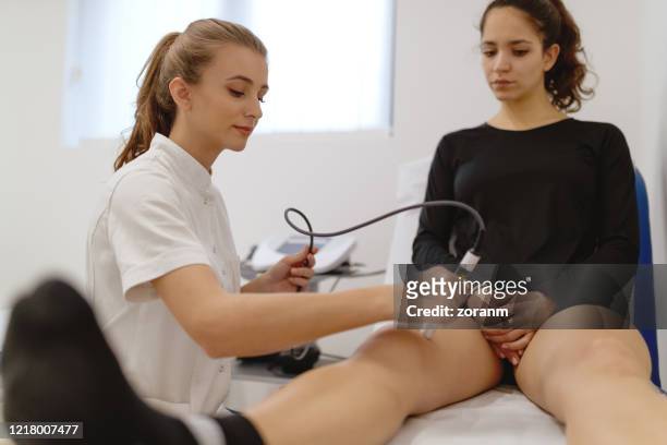 sjukgymnast som applicerar laserterapi på patientens knä - människoknä bildbanksfoton och bilder