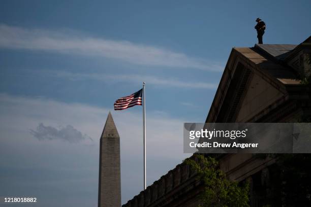 Security stands watch atop the U.S. Treasury Building as demonstrators march during a protest against policy brutality and racism on June 6, 2020 in...