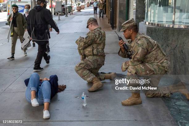 Woman is assisted by National Guard troops after she collapsed on the sidewalk coughing and having difficulty breathing as people continue to protest...