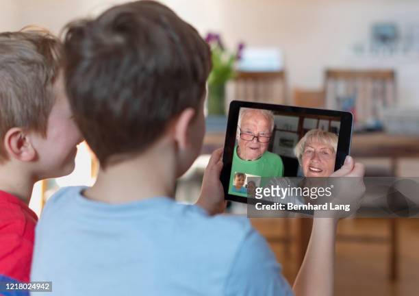 brothers video calling with grandparents through tablet computer - frat boys stock pictures, royalty-free photos & images