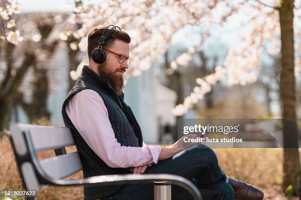 man listening to podcasts on his smart phone - podcast headphones stock pictures, royalty-free photos & images