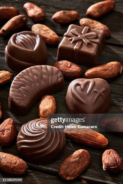 variety of bombones and cocoa beans on a rustic table - bombones chocolate stock-fotos und bilder