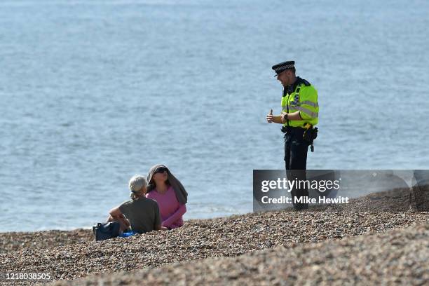 Police officer asks members of the public to leave the beach on April 10, 2020 in Brighton, United Kingdom. The Coronavirus pandemic has spread to...