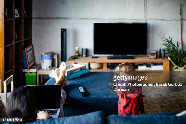 a father using laptop and watching tv with his daughter - family watching tv from behind stockfoto's en -beelden