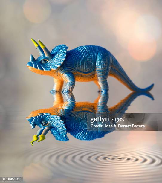 toy dinosaur reflected on the water illuminated by sunlight. - fiktionale figur stock-fotos und bilder
