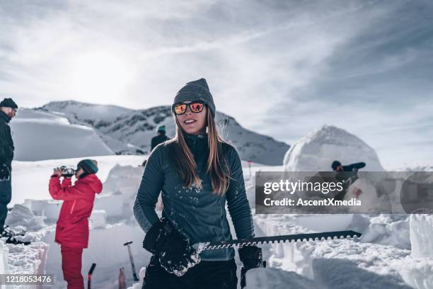 young woman carves snow to build igloo - igloo stock pictures, royalty-free photos & images