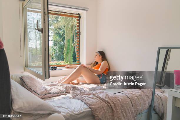 pensive teenage girl looking out of her window. - sick window stock-fotos und bilder