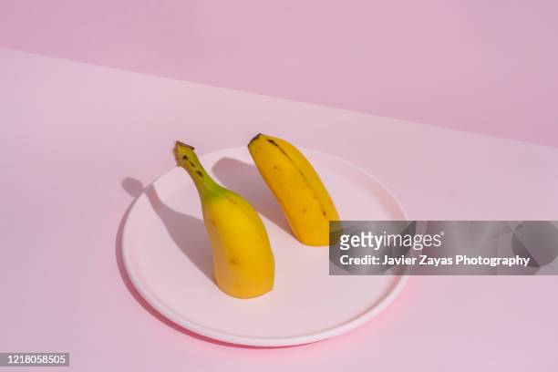 halved banana on a pink plate - halved stockfoto's en -beelden