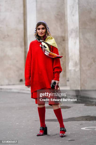 Angela Rozas Saiz wears a Bimba Y Lola scarf over the head, a red wool oversize pullover, a Dior Saddle bag, red shorts, red long socks, bejeweled...