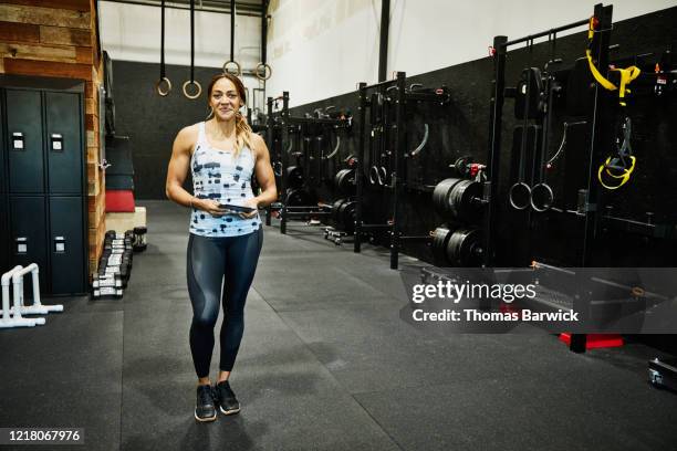 portrait of smiling gym owner holding digital tablet in gym - woman standing exercise stock-fotos und bilder