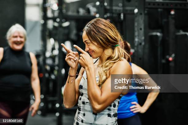 smiling fitness instructor encouraging class during workout in gym - incoraggiamento foto e immagini stock
