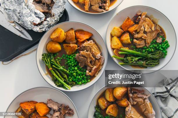 overhead view of plates served up with roast pork and trimmings - sunday roast stock pictures, royalty-free photos & images