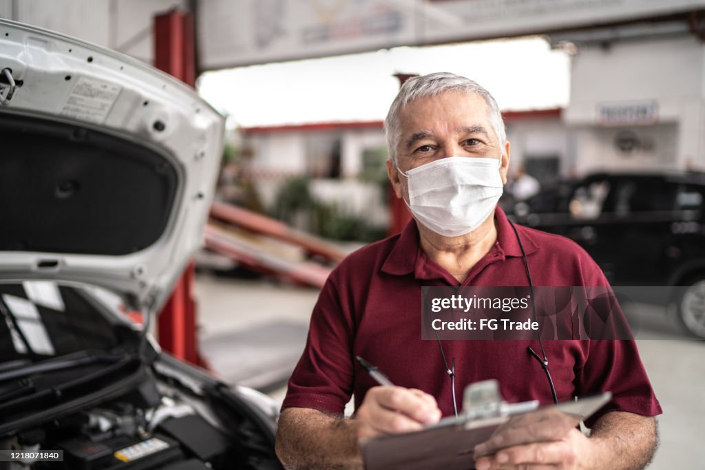 Retrato de mecânico de automóvel homem idoso com máscara facial em oficina de reparos