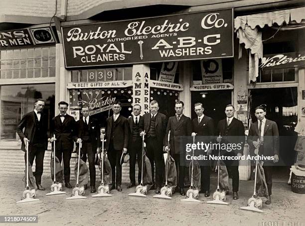 Vintage portrait of salesmen in sales department of Burton Electric Company posing with their Burton vacuum cleaners in front of the company's San...