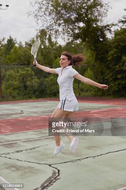 young female full length jump on hard green and red tennis court - vintage tennis player stock pictures, royalty-free photos & images