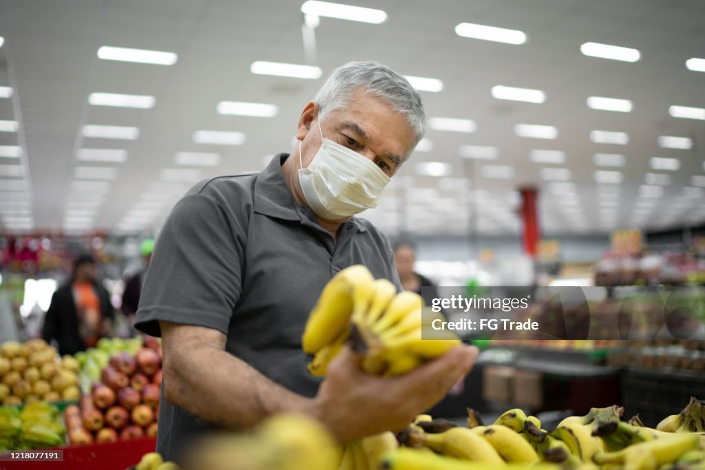 Hombre mayor con máscara médica desechable de compras en supermercado