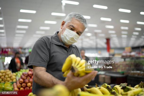 senior man with disposable medical mask shopping in supermarket - market retail space stock pictures, royalty-free photos & images