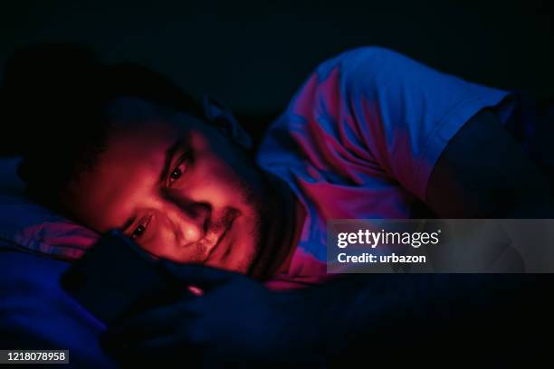 man using phone before bedtime - pandemic loneliness stock pictures, royalty-free photos & images