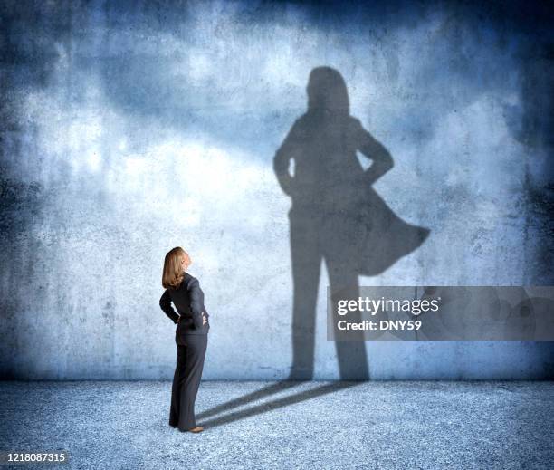 shadow of woman wearing a hero's cape - hero silhouette stock pictures, royalty-free photos & images