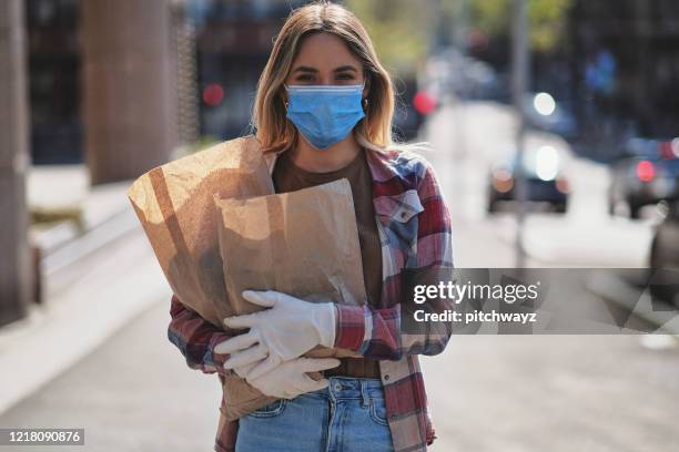 joven en la calle, durante la pandemia de covid-19 - máscara quirúrgica fotografías e imágenes de stock