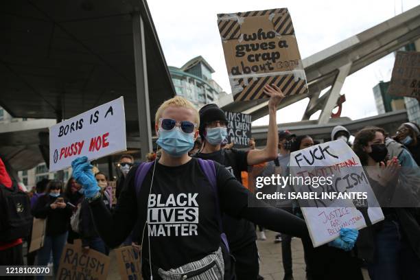 Protesters wearing protective face masks wait with their placards as they prepare to attend a demonstration outside the US Embassy in London on June...