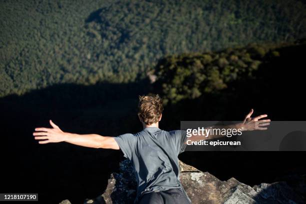 young man leaning over the edge of a cliff - katoomba falls stock pictures, royalty-free photos & images
