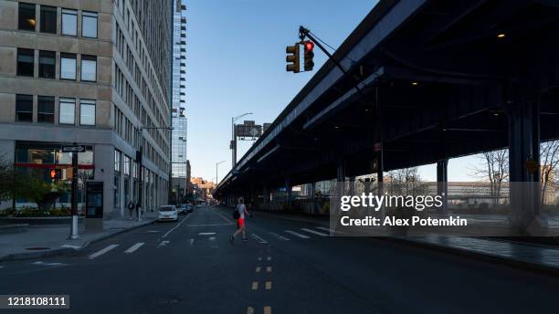 die frau, die die south street unter dem fdr-antrieb überquert, ist wegen des ausbruchs der covid-19-pandemie menschenleer. - fdr drive stock-fotos und bilder