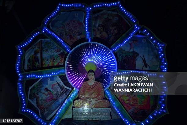 This picture shows a display featuring a seated Buddha during Poson Poya festival in Colombo on June 7, 2020. - Poson Poya is an annual Buddhist...