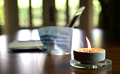 Burning candle on top of table with medical face mask at the background.