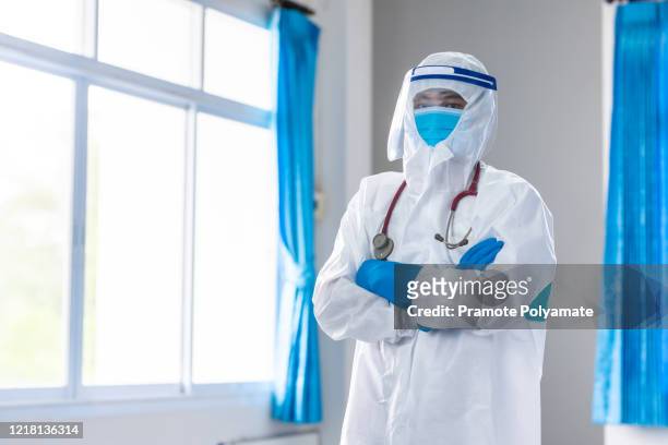 portrait confident doctor in protective ppe suit wearing face mask and eyeglasses in hospital - microbiologist fotografías e imágenes de stock