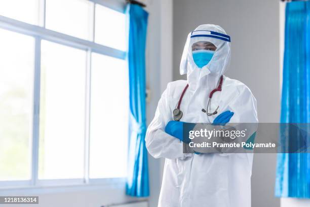 portrait confident doctor in protective ppe suit wearing face mask and eyeglasses in hospital - microbiologist stock pictures, royalty-free photos & images